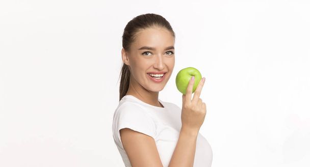 Молодая леди держит яблочный фрукт позируя на белом фоне, Панорама
 - Фото, изображение