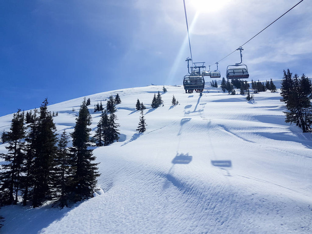 Funiculary s lyžaři jít na vrchol zasněžené hory za slunečného dne. Lyžařské a snowboardové středisko v rakouských Alpách.  - Fotografie, Obrázek