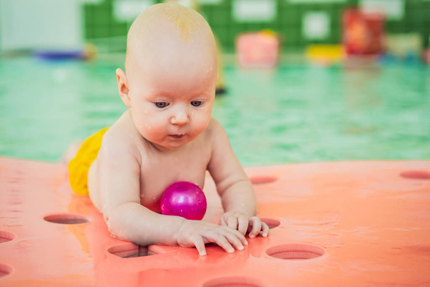 Belle mère enseignant bébé fille mignonne comment nager dans une piscine. Enfant s'amuser dans l'eau avec maman
 - Photo, image