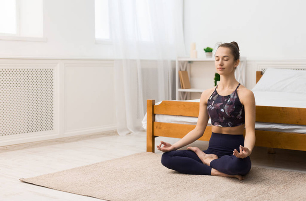 Giovane donna che fa yoga a casa nella posizione del loto
 - Foto, immagini