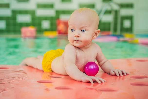 Beautiful mother teaching cute baby girl how to swim in a swimming pool. Child having fun in water with mom - Photo, Image
