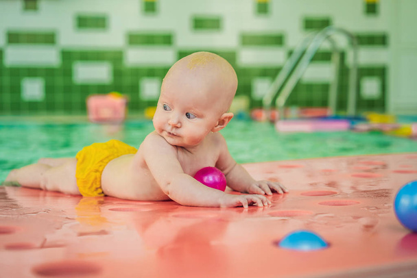 Beautiful mother teaching cute baby girl how to swim in a swimming pool. Child having fun in water with mom - Foto, Bild