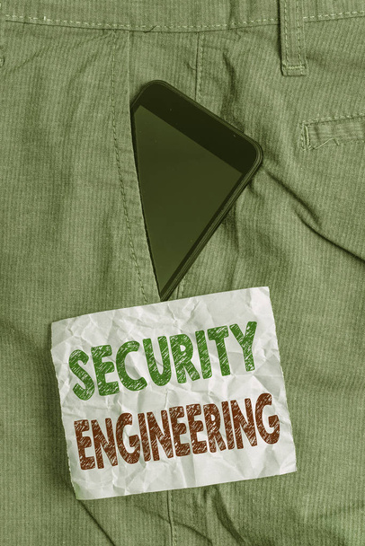 Handwriting text Security Engineering. Conceptual photo focus on the security aspects in the design of systems Smartphone device inside formal work trousers front pocket near note paper - Photo, Image