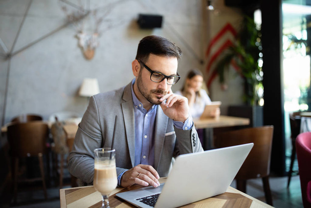 Porträt eines erfolgreichen Unternehmers, der im Café vor einem Laptop sitzt. - Foto, Bild