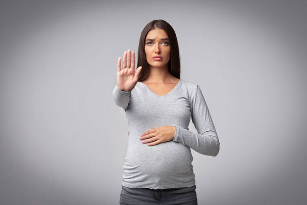 Schwangere gestikulierende Frau schaut nicht mehr in die Kamera, die im Studio steht - Foto, Bild