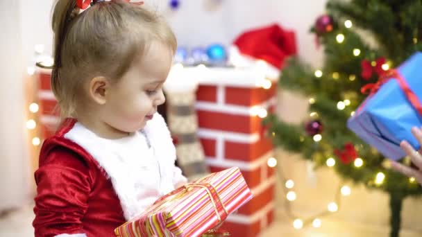 baby and pregnan mom hang red ball toy on Christmas tree. happy childhood concept. child and mother decorate tree with christmas balls. small child and a parent are playing by Christmas tree. - Video