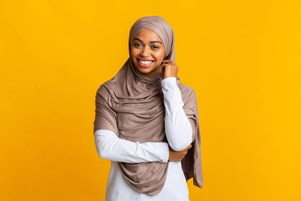 Shy black muslim girl in headscarf posing over yellow background - Фото, изображение