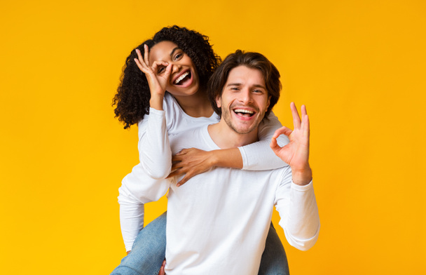 Happy interracial couple showing ok gesture and having fun together - Photo, Image