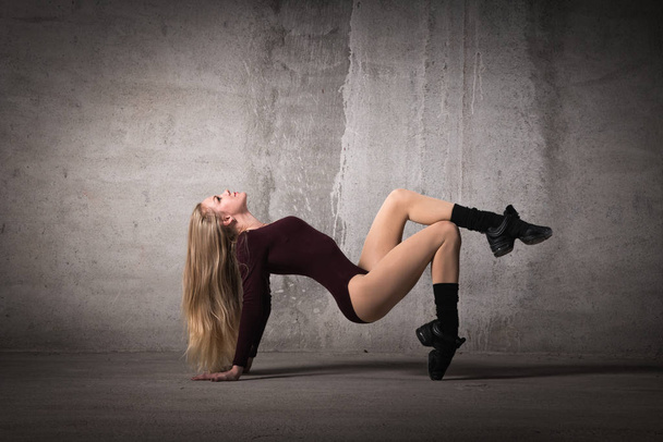 Blonde dancer stands on fingers on a gray background, dance pose, dance, body shape, fitness, training, strength - Fotoğraf, Görsel