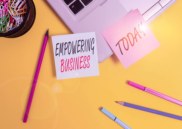 Conceptual hand writing showing Empowering Business. Concept meaning creating an environment that fosters growth of business Laptop sticky notes container pencils markers colored background - Photo, Image