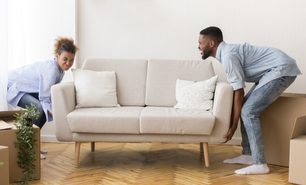 Paar hebt Sofa nach Umzug in leerem Raum - Foto, Bild