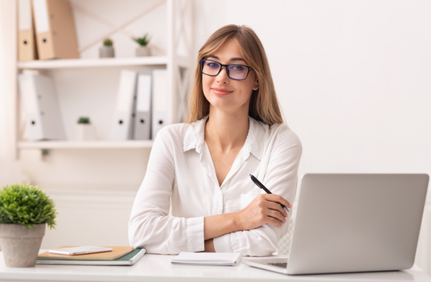 Уверенная предпринимательница, сидящая за рабочим столом ноутбука
 - Фото, изображение