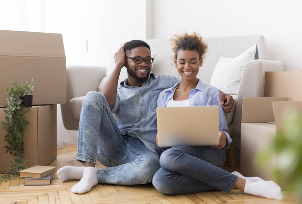 Ευτυχισμένο ζευγάρι που χρησιμοποιεί το lap-top κάθεται στο πάτωμα στο νέο σπίτι - Φωτογραφία, εικόνα