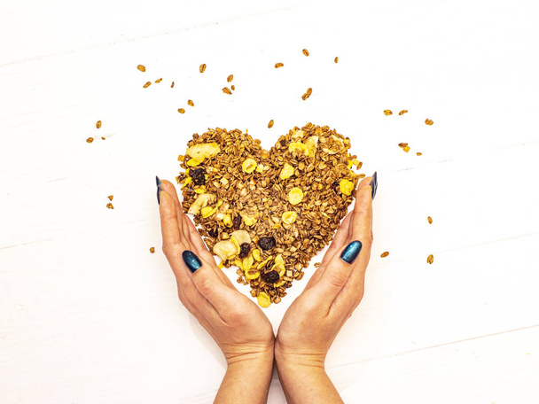 Heart laid out of granola in hands on a white background. - Photo, Image