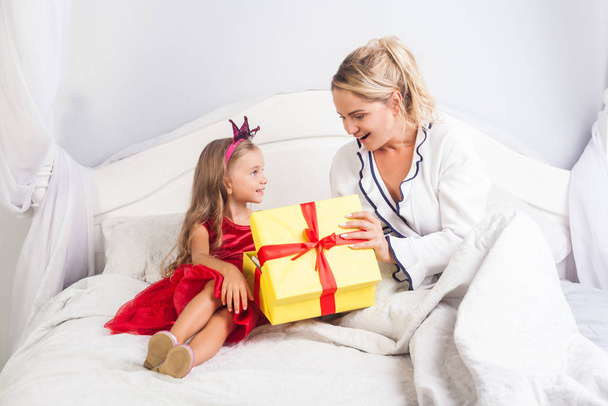 Young mother opening gift box with surprised amazed face, sittin - Fotoğraf, Görsel