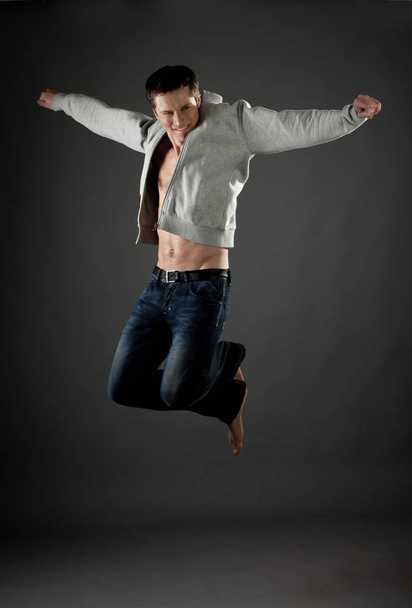 Man in gray jacket poses in jump - Фото, зображення