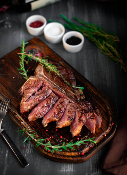 grilled sliced T-bone steak on wooden board with seasonings - Fotó, kép