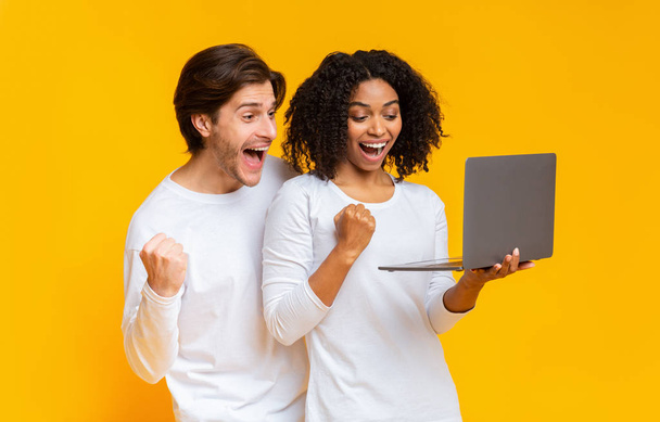 fröhliches gemischtes Paar feiert Sieg mit Laptop - Foto, Bild
