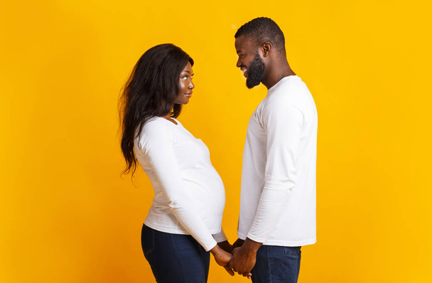 Terhes nő és férfi fogják egymás kezét, egymásra néznek - Fotó, kép