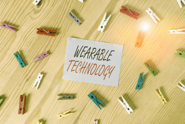 Znak tekstowy pokazujący Wearable Technology. Biznesowe zdjęcie pokazujące urządzenia elektroniczne, które mogą być noszone jako akcesoria Kolorowe szpilki do ubrań puste przypomnienie drewniana podłoga tło biuro - Zdjęcie, obraz