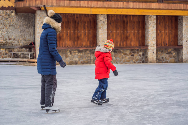 young mother teaching her little son ice skating at outdoor skating rink. Family enjoy winter on ice-rink outdoors - Fotografie, Obrázek