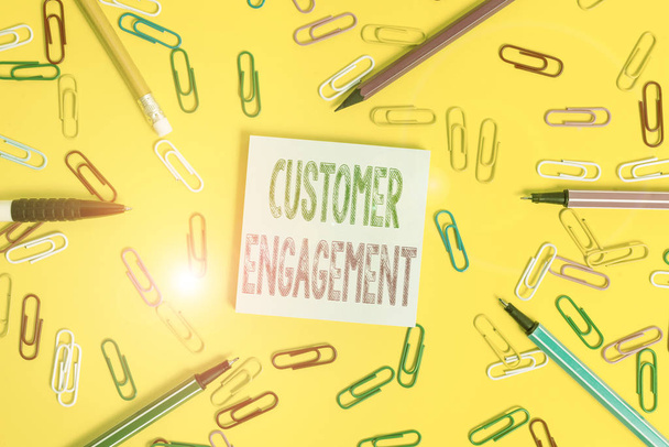 Handwriting text writing Customer Engagement. Conceptual photo the emotional connection between a customer and a brand Flat lay above empty paper with copy space pencils and colored paper clips - 写真・画像