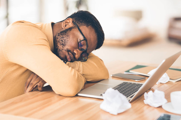 Estresado afroamericano gerente acostado en el escritorio
 - Foto, Imagen