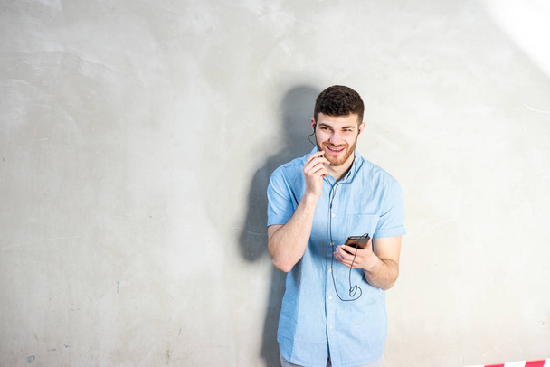 Πορτρέτο του νεαρού που μιλάει με κινητό τηλέφωνο και ακουστικά  - Φωτογραφία, εικόνα