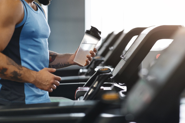 Sportsman drinking water during cardio workout on treadmill - Photo, Image
