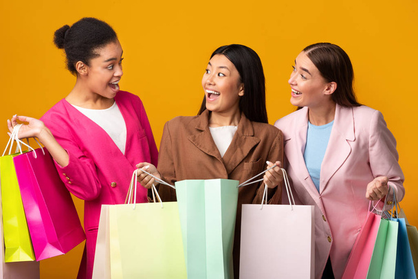 Trois femmes heureuses tenant des sacs Shopper debout sur fond jaune
 - Photo, image