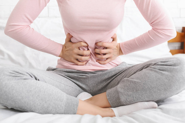 Žena trpící bolestí břicha, sedí v posteli - Fotografie, Obrázek
