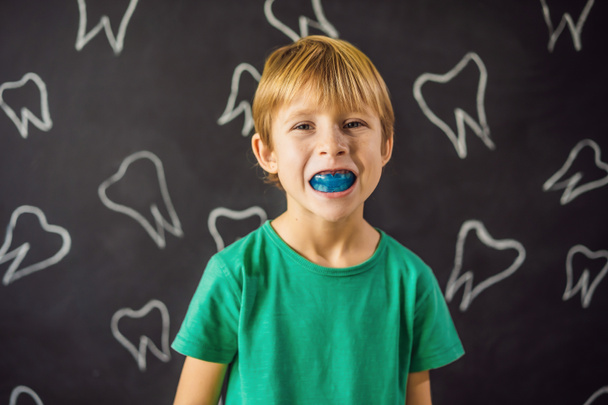 Un niño de seis años muestra un entrenador miofuncional. Ayuda a igualar el crecimiento de los dientes y la mordedura correcta, desarrollar hábito de respiración bucal. Corrige la posición de la lengua
 - Foto, Imagen