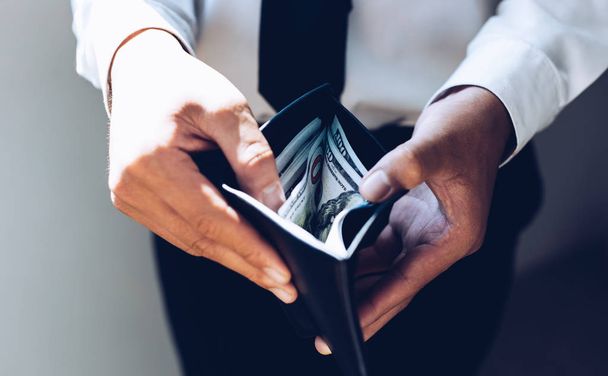 Die Hand des Geschäftsmannes trägt eine schwarze Handtasche und hat eine Menge Dollarnoten, Geld-Konzept. - Foto, Bild