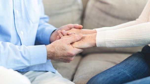 Unrecognizable elderly couple holding hands at home - Photo, Image