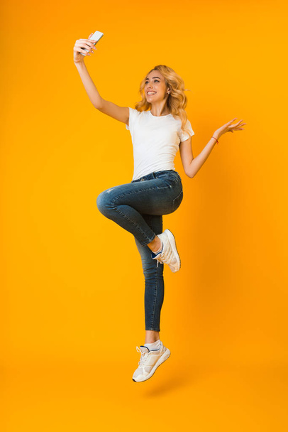 Happy woman in casual clothes jumping and making selfie - Foto, Imagem