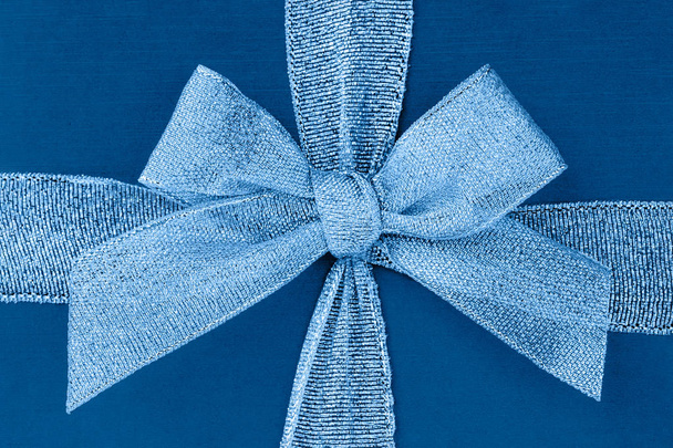 Blue gift box with ribbon and bow. Top view, background. Color of the year 2020 Classic Blue toned. - Valokuva, kuva