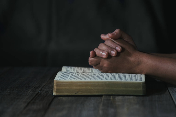 Manos dobladas en oración sobre una Santa Biblia en concepto de la iglesia para la fe
 - Foto, Imagen