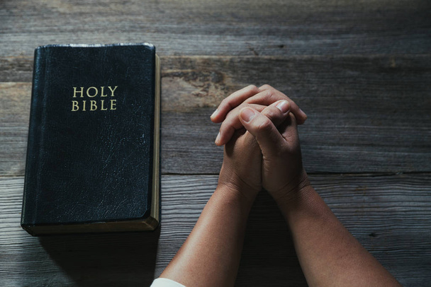 Hands folded in prayer on a Holy Bible in church concept for faith - Foto, Imagem