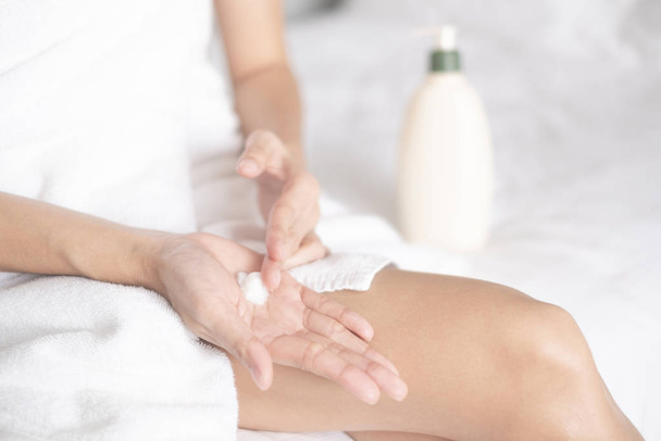 Woman applying moisturizing cream/lotion on hands on white bed, beauty concept - Photo, Image