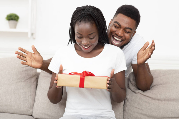 Loving black guy surprising his girlfriend with gift at home - Photo, Image