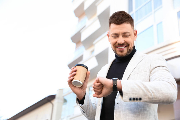 Businessman with cup of coffee on city street in morning - Foto, Bild