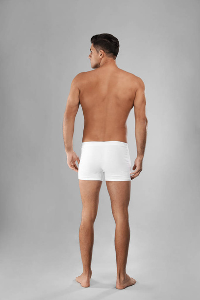 Handsome man in white underwear on light grey background, back v - 写真・画像