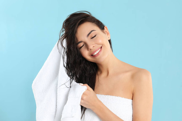 Young woman drying hair with towel on light blue background - Foto, immagini