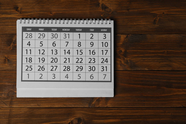 Papírový kalendář na dřevěném stole, horní pohled - Fotografie, Obrázek