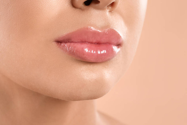 Young woman with beautiful full lips on peach background, closeup - Valokuva, kuva