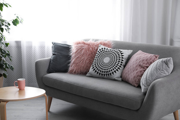 Soft pillows on modern sofa in living room - Фото, изображение