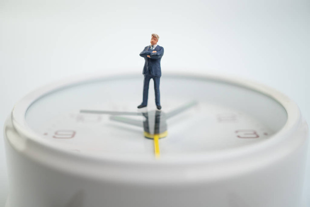 Figure businessmen are thinking And standing on the white watch face by the watch face showing the time. Concept of time management. - Фото, изображение