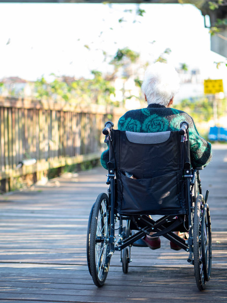 Пожилые азиатки, пожилые люди, сидят на инвалидных колясках на открытом воздухе
 - Фото, изображение