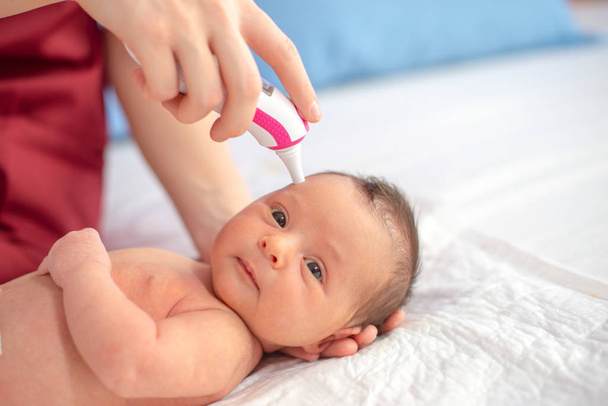 新生児の温度をチェックするデジタル温度計を持つ医師 - 写真・画像
