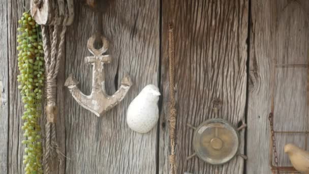 Ξύλινος τοίχος διακοσμημένος με vintage αξεσουάρ θαλάσσης, άγκυρα, πυξίδα και σχοινί. Σάπιος παλιός ξύλινος τοίχος και ρετρό ναυτική διακόσμηση για κήπο. Μοντέρνο κομψό φόντο. - Πλάνα, βίντεο